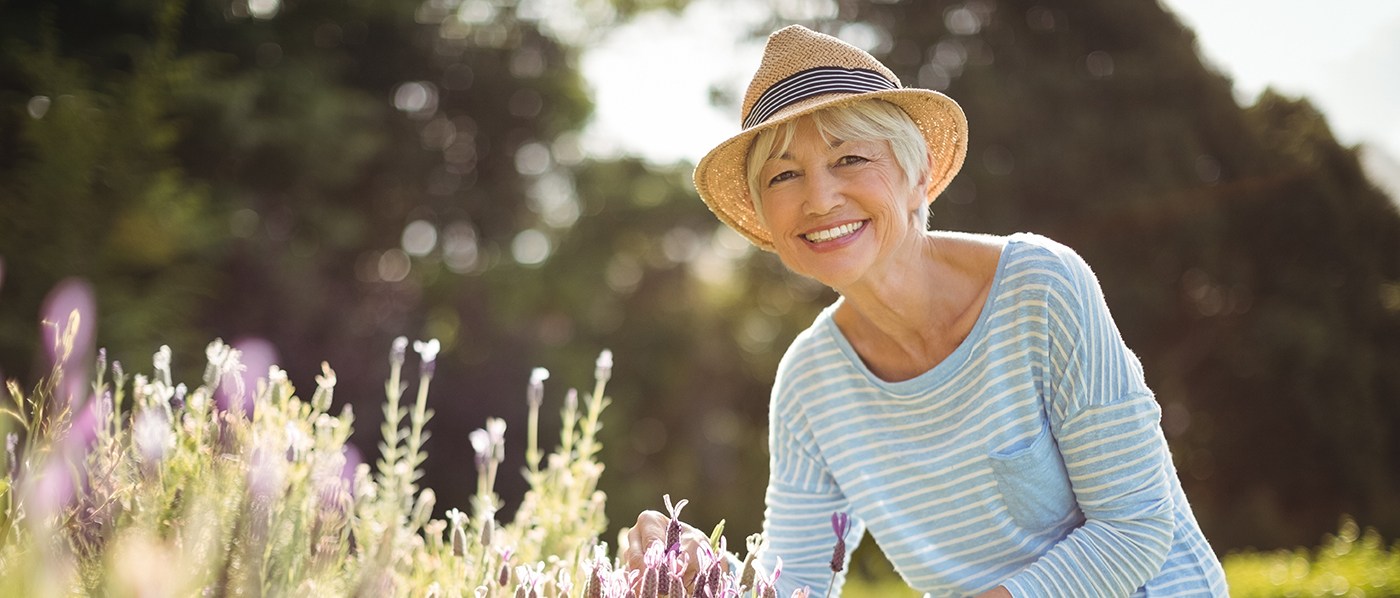 Woman in straw hat smiling while gardening