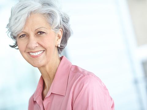 Woman in gray hair with pink shirt smiling