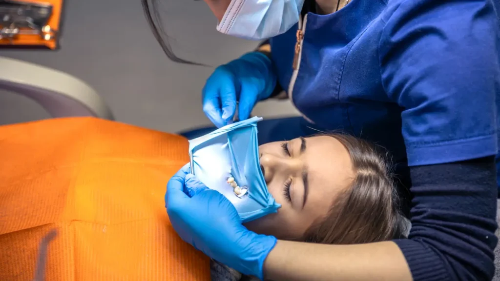 dentist treats childs tooth using rubber dam closeup tooth treatment 1 1 - Dentique Dental Care