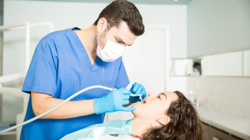 young woman receiving dental treatment from male dentist clinic 1 - Dentique Dental Care